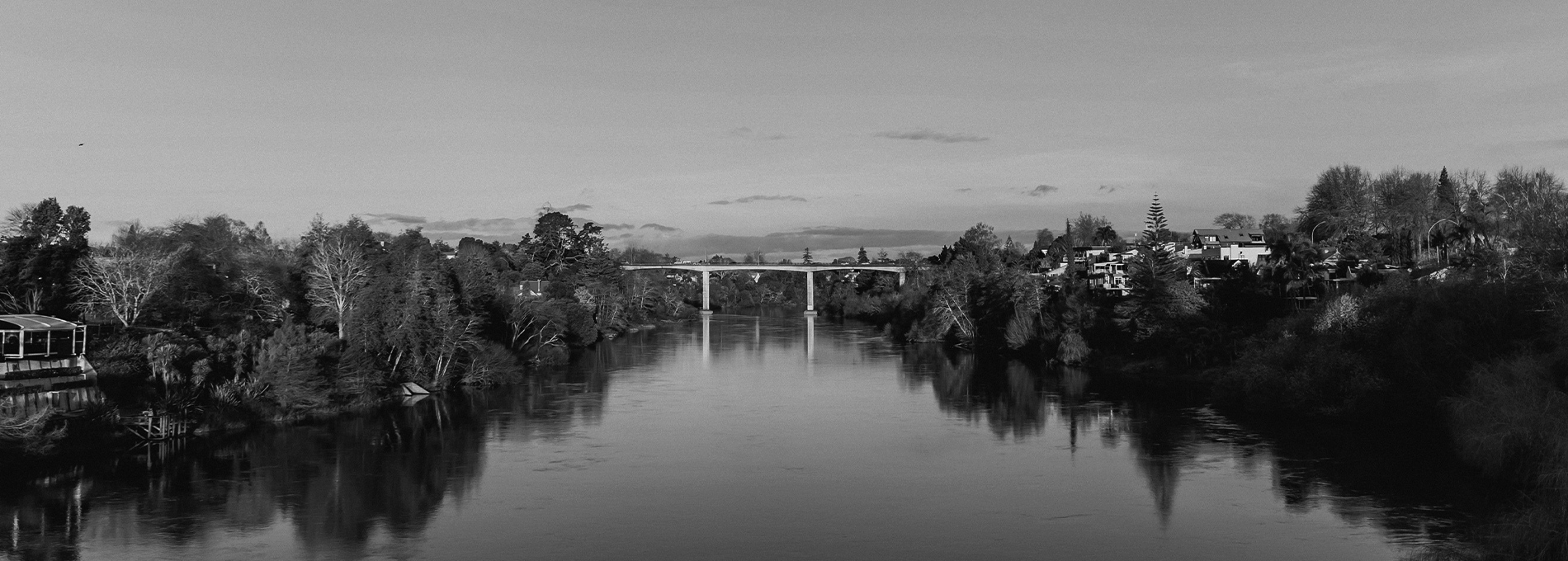 Black and white wide camera angle in Hamilton at Waikato river with a bridge