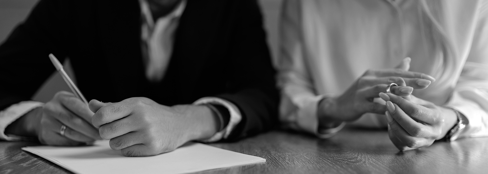 Black and white husband signing divorce papers as wife sits next to him